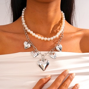 Close-up of double-layer faux pearl necklace with five silver heart pendants on model