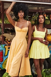 Detail eines pfirsichfarbenen Maxikleides mit Schlitz und gelbem Minikleid mit Plissee