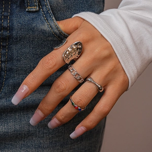 Detail of silver bohemian stacking ring set with embedded colorful gemstones on finger