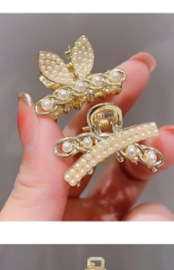 Detail von goldenen Haarklammern aus Metall mit Perlen im Schmetterling-Design