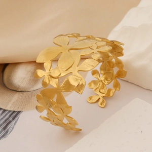 Close-up of golden hollow flower cuff bracelet with matte finish and floral pattern