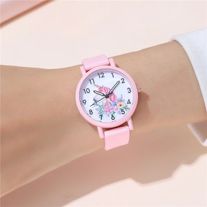 Close-up of pink silicone watch featuring a floral unicorn dial on child's wrist