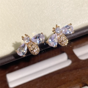 Macro view of gold bee stud earrings with shimmering pear-shaped zircon wings and body