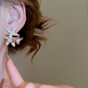 Detailed close-up of a floral earring featuring pink petals and a central white pearl