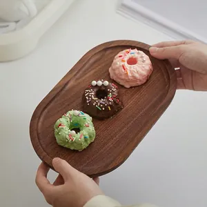Minimalistisch ovaal serveerdienblad van zwart walnoothout voor afternoon tea en gebak