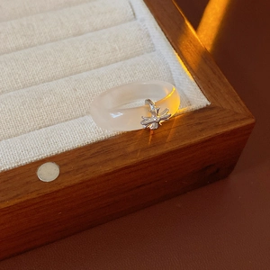 Close-up of a white chalcedony ring featuring a vintage silver cross pendant on display