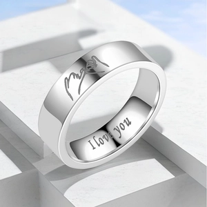 Detail of silver titanium steel ring with 'I love you' engraving on white pedestal