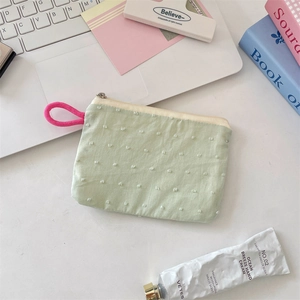 Macro shot of a light green cosmetic pouch with white polka dots on a desk setting