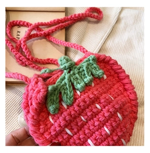 Detailaufnahme der handgestrickten Erdbeertasche mit weicher Häkelstruktur in Rosa