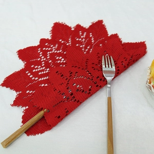 Red lace placemat with leaf-shaped cutouts on white fabric background for Christmas