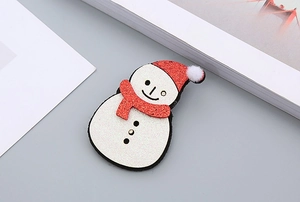 Détail d'une pince à cheveux bonhomme de neige pailletée avec bonnet rouge de fête