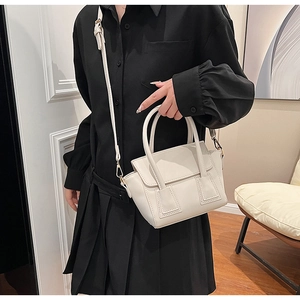 Detail of cream white leather bucket bag with gold hardware and adjustable strap