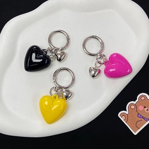 Creative resin heart-shaped keychains in black, rose red, and yellow on a white tray