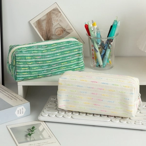 Detail of green and cream woven stationery pouches with textured fabric and metal zippers