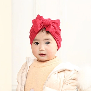 Close-up of baby turban hat in red cashmere-style fabric with a large double bow detail
