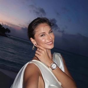 Abito elegante in raso a fiori con gioielli a catena d'oro e orologio di lusso in spiaggia