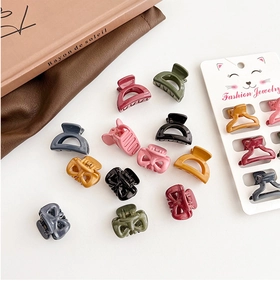 Flat lay of mini Morandi color plastic hair claws with various shapes on a white background