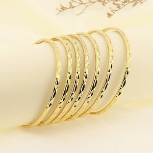 Stackable gold-plated stainless steel bangles with elegant diamond-cut textured pattern