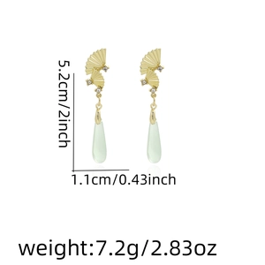 Macro detail of Chinese fan long tassel earrings with green teardrops and rhinestones