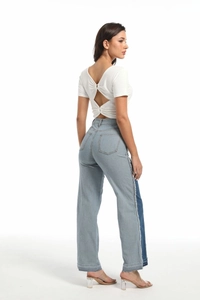 Detail of high-waist jeans featuring blue contrast patchwork and raw fringe edges