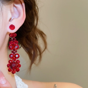 Detail of elegant red beaded tassel earrings worn by a model in soft lighting