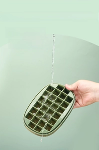 Detail of dark green 24-grid ice box being rinsed with water to show easy clean feature