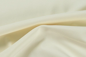 Close-up of high-quality light beige lace fabric with detailed weave and soft texture