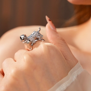 Close-up of a silver puppy ring with a crystal bow and pearl collar on a model finger
