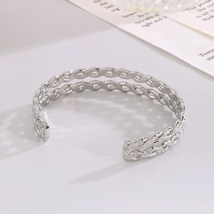 Close-up of a double-layered twisted silver steel cuff bracelet with a woven texture