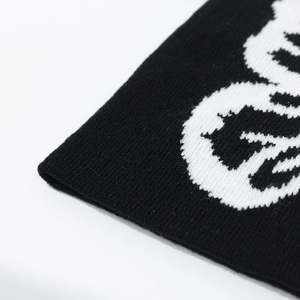 Detail shot of black knitted beanie with white skull pattern and soft fabric texture