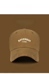 Detailed view of white embroidery and distressed ripped brim on a brown cotton baseball cap