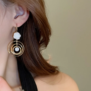 Détail de boucles d'oreilles dorées avec fleur blanche et zircon brillant sur modèle
