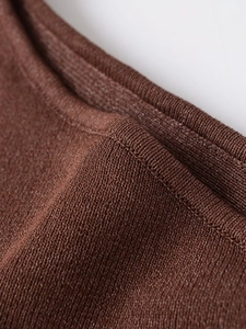 Macro shot of dark brown knitted fabric showing premium texture and fine stitching detail