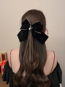 Dettaglio elegante fiocco in velluto nero con catene a frangia d'argento e perle