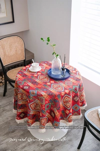 Detail of red jacquard round tablecloth featuring bohemian geometric patterns and white tassels