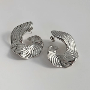 Détail de boucles d'oreilles en acier titane argenté avec texture coquillage en spirale