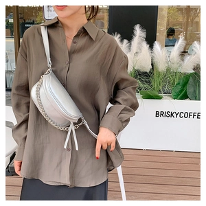 Silver crossbody bag with litchi grain texture and metallic chain detail on a model