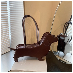 Creative dachshund-shaped brown leather tote bag placed on a book in a lifestyle setting