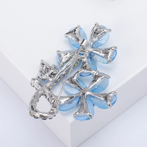 Detailed back view of a silver flower brooch with blue rhinestones and pin fastener