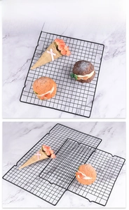 Close-up of rectangular black non-stick cooling rack with mesh grid and support legs