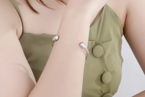 Polished silver cylinder open bangle with rhinestone detail worn on a female wrist