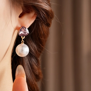 Détail d'une boucle d'oreille vintage avec cristal violet et perle sur un mannequin