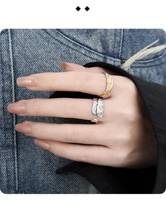 Detail of silver feather ring and mixed metal wavy ring worn on denim background