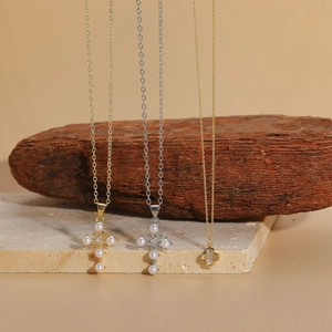 Detailed shot of gold and silver cross necklaces with pearls and a clover pendant
