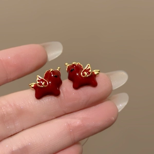 Detailed macro view of 18k gold plated unicorn stud earrings with red enamel