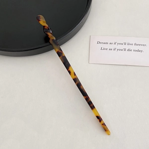 Macro shot of amber acetate hair stick with unique spiral twist design and marble texture