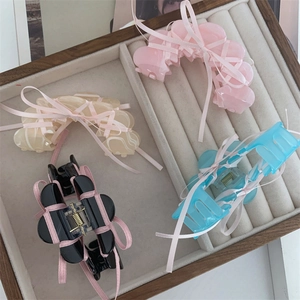 Detailed view of acetate hair claws in pink, beige, black, and blue with ribbon bows