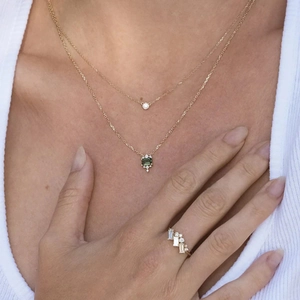 Detail of gold layered necklaces with emerald and diamond pendants and matching ring set