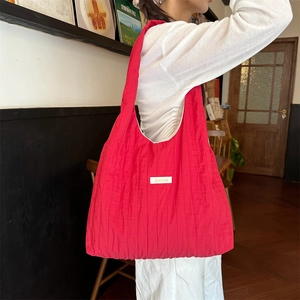 Close-up of red quilted tote bag with white woven label showing soft texture and stitching