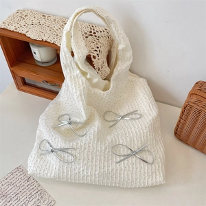 Dettaglio borsa shopper bianca a pois con fiocco argento in un ambiente domestico caldo